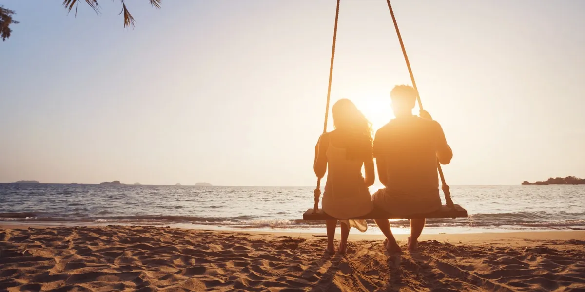 A couple swinging together at sunset.